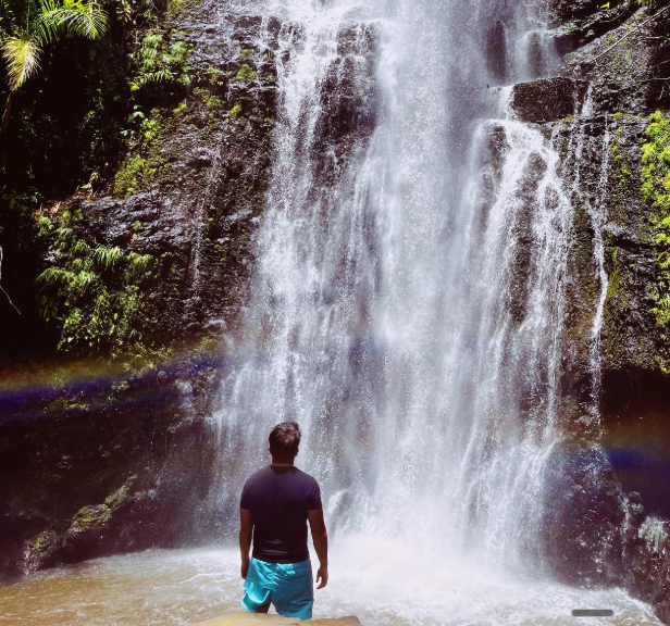 Standing beneath a tropical waterfall